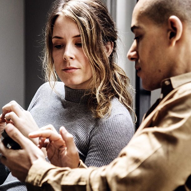 A man showing a woman information on his smartphone 