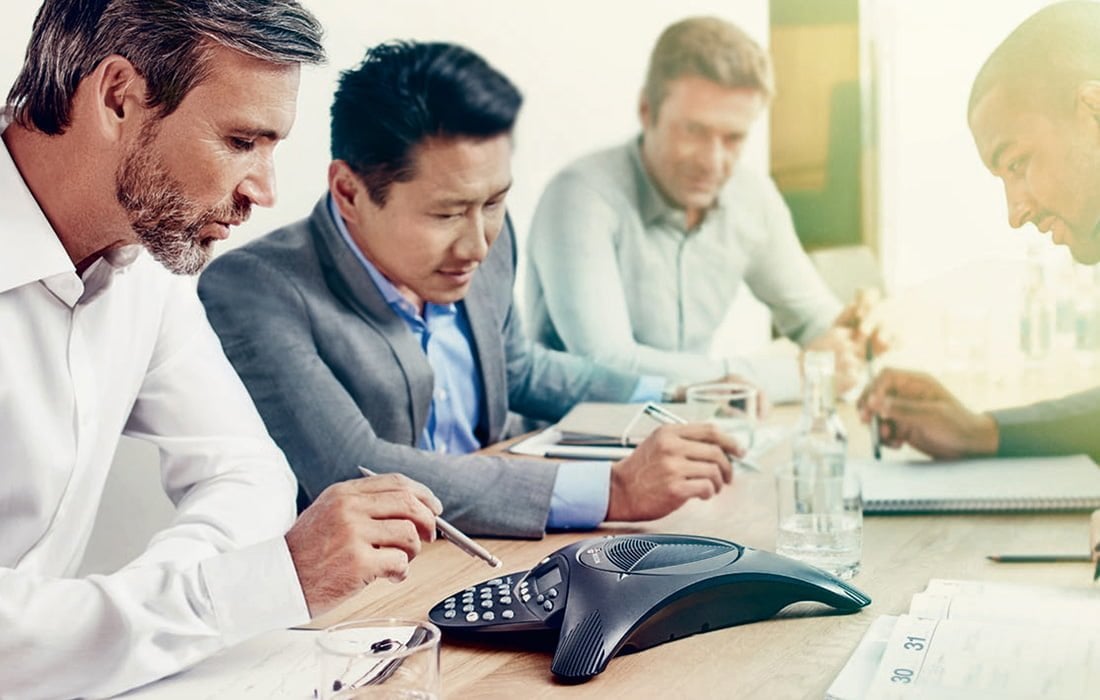 A group of people sitting at a table on a conference call